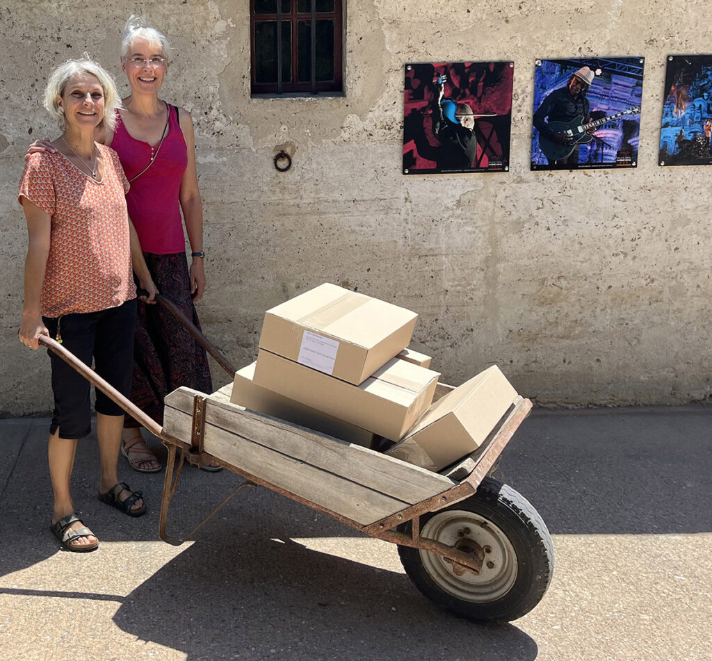 photo de 2 femmes portant une brouette pleine de livres encore dans des cartons
